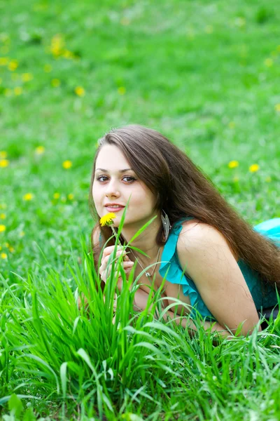 タンポポの芝生でリラックスを持つかなり若い女の子 — ストック写真