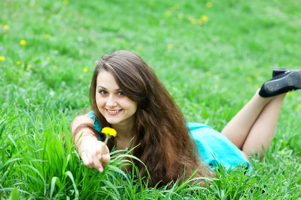 Krásná dívka s pampelišky relaxaci na trávníku — Stock fotografie