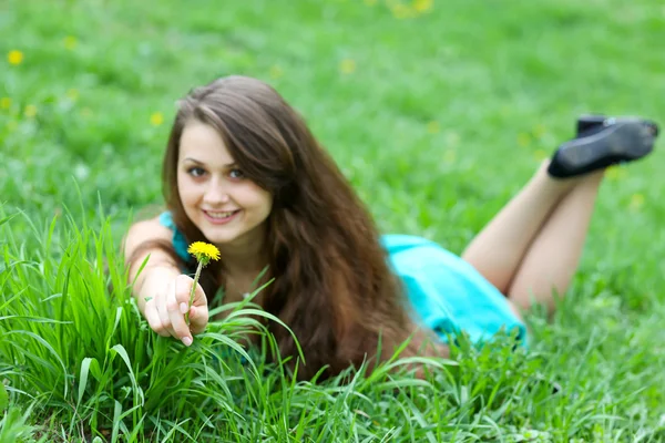 Menina lindo com dente de leão relaxante no gramado — Fotografia de Stock