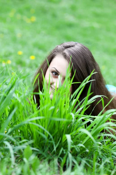 Jolie jeune fille souriante se cachant derrière des lames vert vif de — Photo