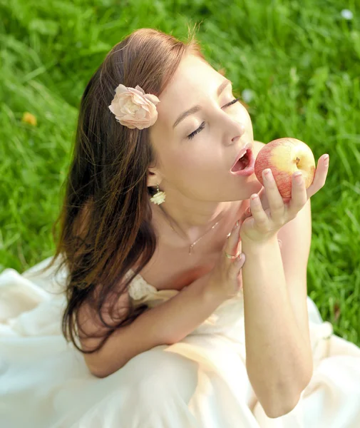Morena chica joven con una manzana en el parque de verano disfrutando — Foto de Stock