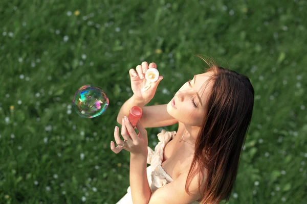 Mladá dívka foukání mýdlové bubliny v létě zelený park — Stock fotografie