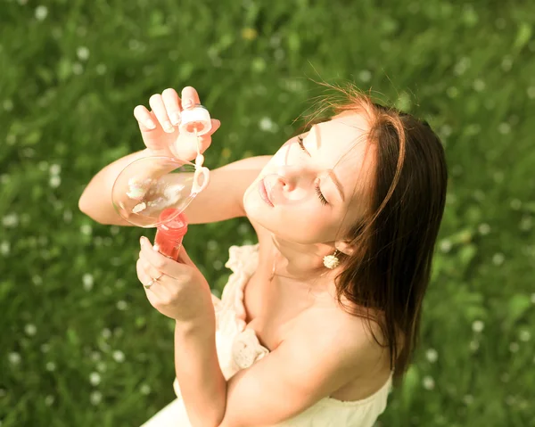 Chica joven soplando burbujas de jabón en el parque verde de verano — Foto de Stock