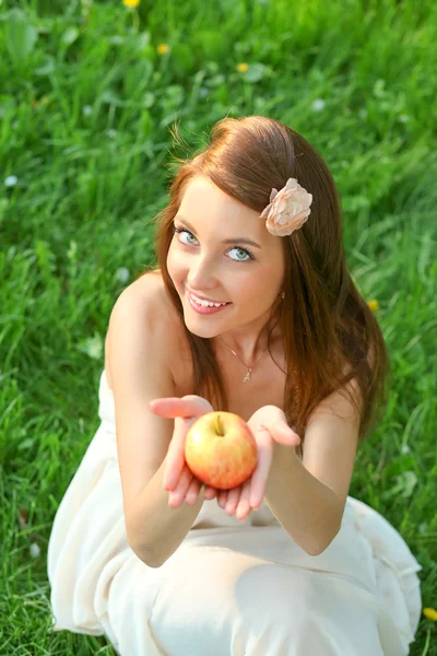 Morena chica joven con una manzana en el parque de verano disfrutando —  Fotos de Stock