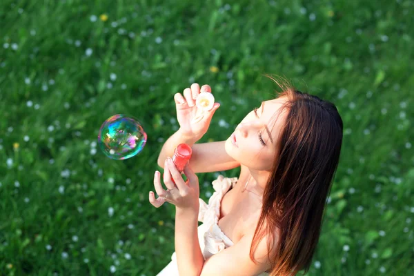 Junges Mädchen pustet Seifenblasen im sommergrünen Park — Stockfoto