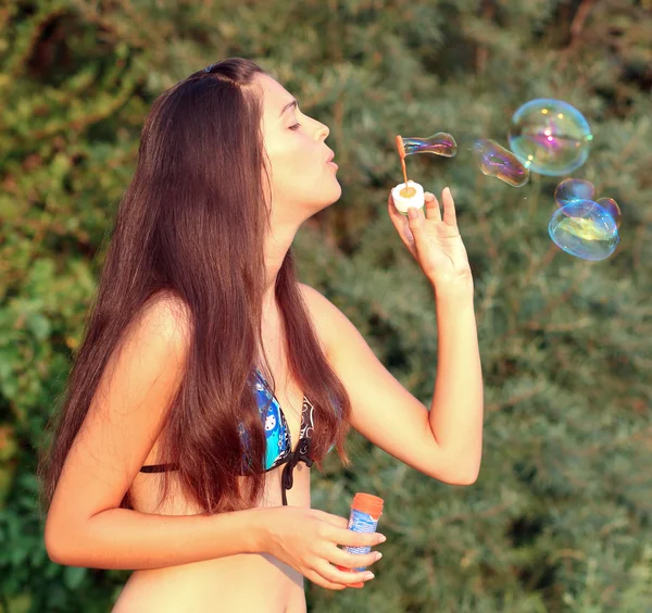 Красивая женщина надувает мыльные пузыри — стоковое фото