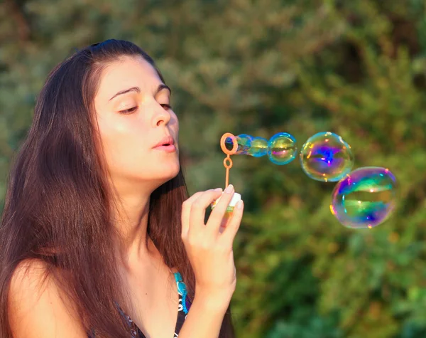 Красива жінка надуває мильні бульбашки — стокове фото