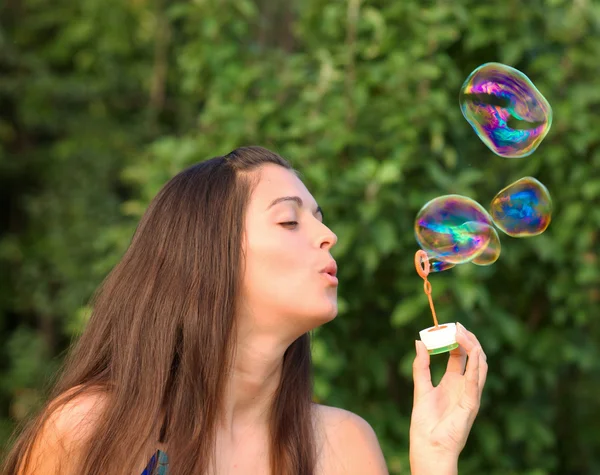 Pretty woman inflating soap-bubbles — Stock Photo, Image