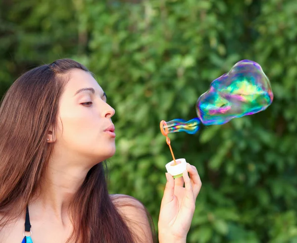Porträtt av attraktiv ung flicka blåsa färgglada såpbubblor utomhus — Stockfoto