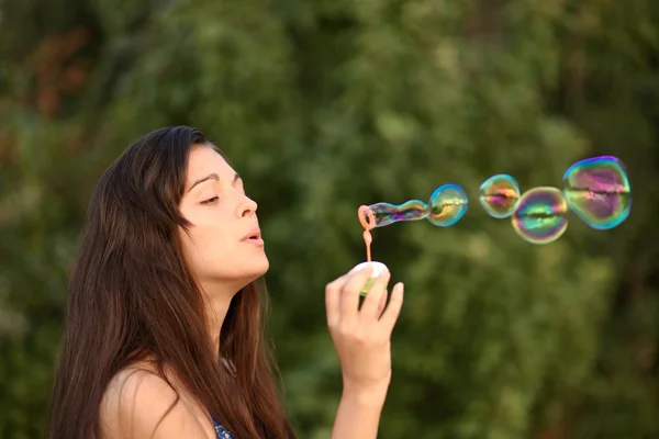 Portrét atraktivní mladé dívky nafukovací barevné mýdlové bubliny venku — Stock fotografie