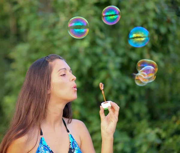 Молодая девушка надувает разноцветные мыльные пузыри — стоковое фото