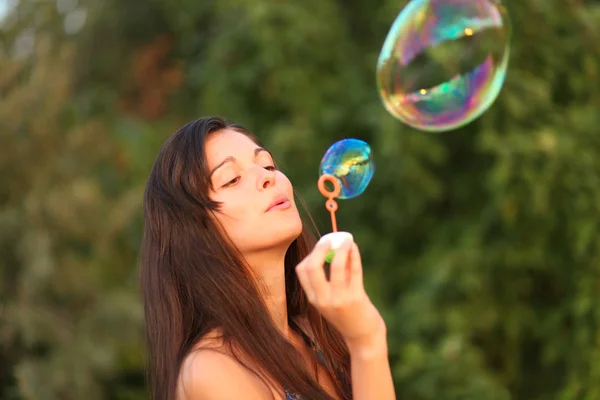 Красивая женщина надувает мыльные пузыри — стоковое фото