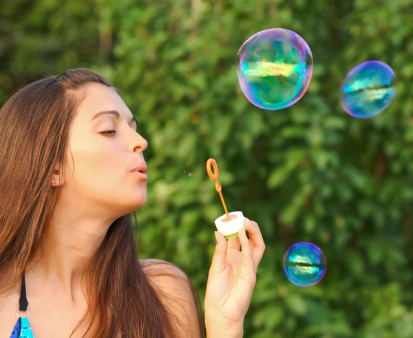 Menina jovem inflando bolhas de sabão coloridas — Fotografia de Stock