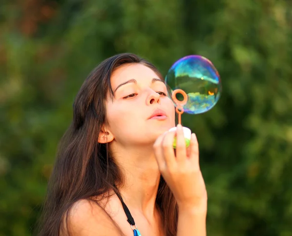 Pretty woman inflating soap-bubbles — Stock Photo, Image