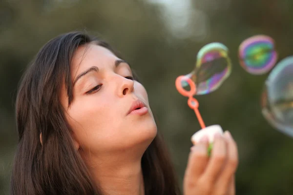 Hübsche Frau beim Aufblasen von Seifenblasen — Stockfoto
