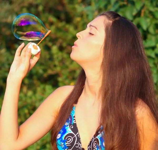 Retrato de chica joven atractiva inflando burbujas de jabón de colores al aire libre —  Fotos de Stock
