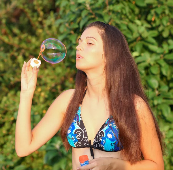 Portrait of attractive young girl inflating colorful soap bubbles outdoor — Stock Photo, Image