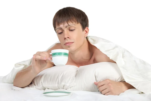 Genç, yatakta yatan ve bir bardak tutan adam — Stok fotoğraf
