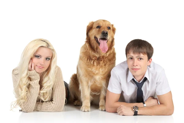 Uma jovem família com um cão no chão, olhando para a câmera — Fotografia de Stock