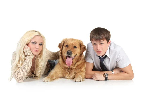 Eine junge Familie mit einem Hund auf dem Boden, der in die Kamera blickt — Stockfoto