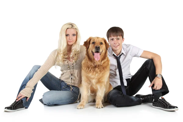Молодая семья с собакой, сидящей на полу, смотрящей в камеру — стоковое фото