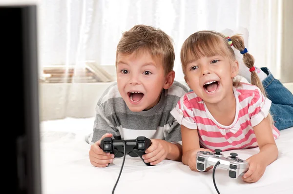 Chica feliz y niño jugando un videojuego —  Fotos de Stock