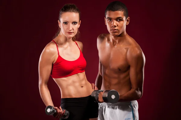 Fuerte pareja joven haciendo ejercicio con pesas —  Fotos de Stock