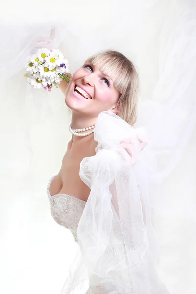 Schöne junge Frau in einem weißen Kleid mit einem Blumenstrauß — Stockfoto