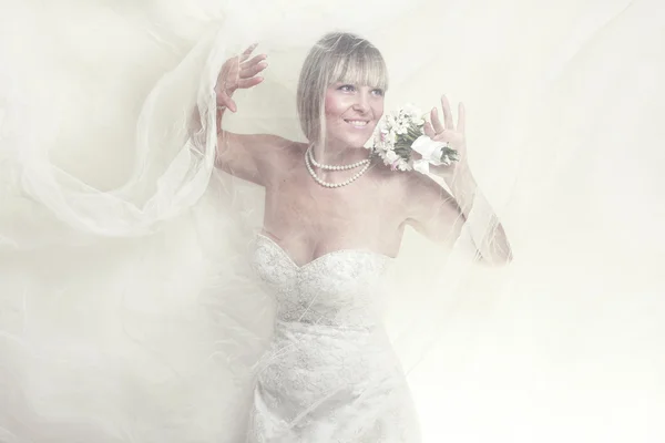 Çiçek buketi olan beyaz elbiseli güzel genç bir kadın. — Stok fotoğraf