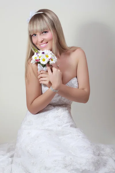Vacker ung kvinna i en vit klänning med en bukett blommor — Stockfoto