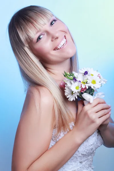 Bela jovem mulher em um vestido branco com um buquê de flores — Fotografia de Stock