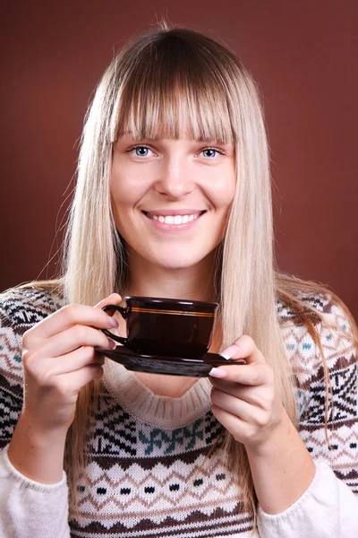 Beautiful blonde with a cup of coffee on a brown background Stock Image