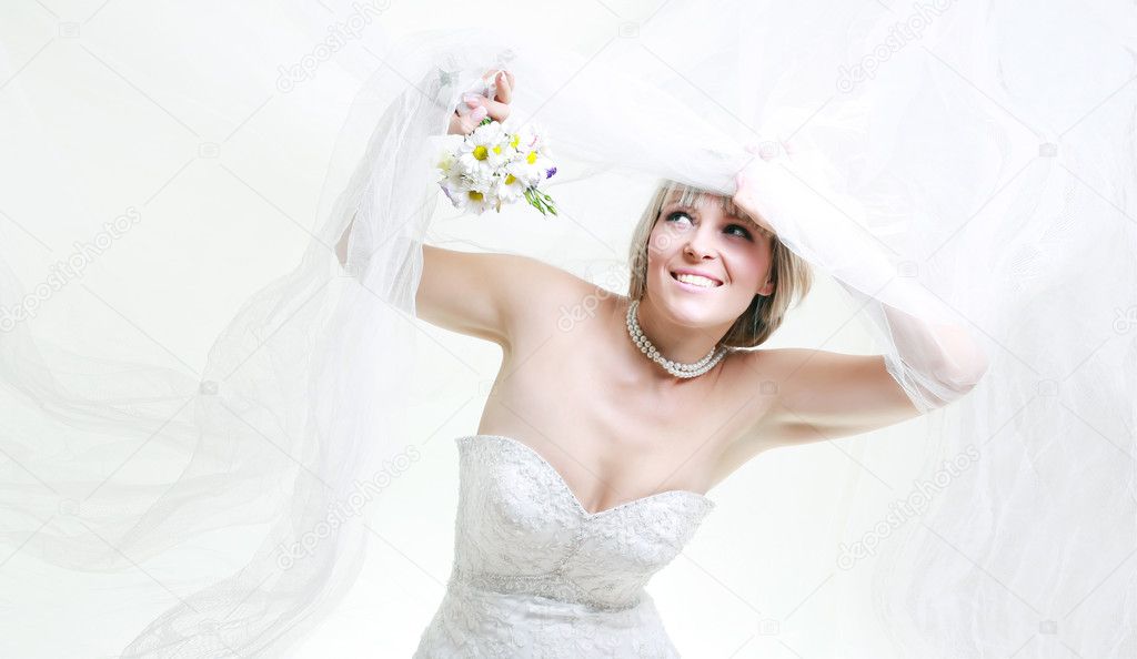 Beautiful young woman in a white dress with a bouquet of flowers