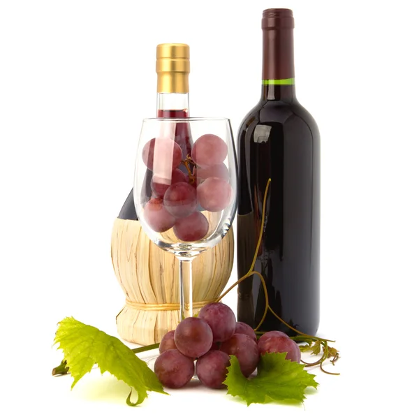 Copo de vinho cheio de uvas e duas garrafas de vinho — Fotografia de Stock
