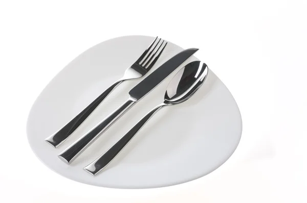 Πιρούνι, κουτάλι και μαχαίρι σε ένα πιάτο πάνω από λευκό — Φωτογραφία Αρχείου