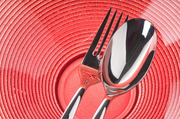 Tenedor y cuchara en plato rojo — Foto de Stock