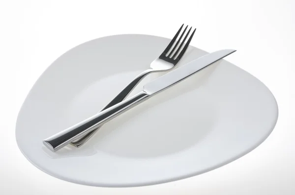Fourchette et couteau sur une assiette blanche — Photo