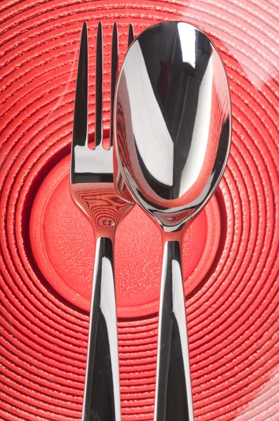 Tenedor y cuchara en plato rojo — Foto de Stock