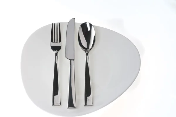 Fourchette, cuillère et couteau sur une assiette blanche — Photo