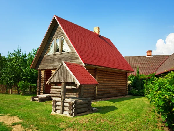 Wooden house and well in the yard — Stock Photo, Image