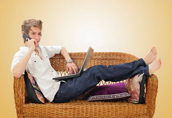 Young man on cell phone in front of laptop — Stock Photo, Image