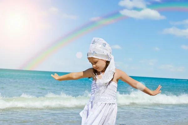 Flicka på stranden med näsduk placera med regnbåge i bakgrunds — Stockfoto