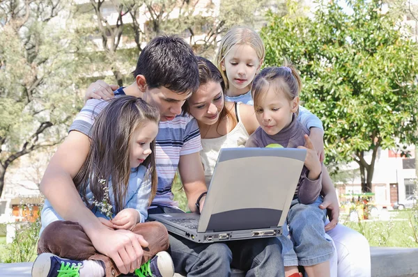 Familjen i parken studera den bärbara datorn — Stockfoto