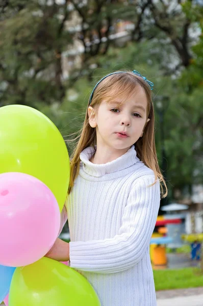 Krásná malá holčička s balónky v parku — Stock fotografie