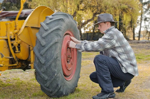 stock image Handsome next to a tractor wheel fixing