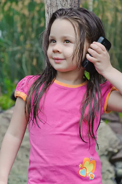 Kleines Mädchen, das mit einem Handy spricht — Stockfoto