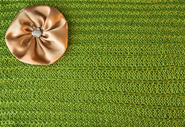 Фон з зеленою в'язаною текстурою і коричневим бантом — стокове фото