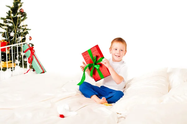 Мальчик с подарком возле новогодней елки — стоковое фото