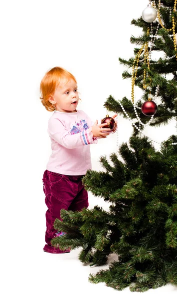 Маленькая девочка украшает новогоднюю елку — стоковое фото