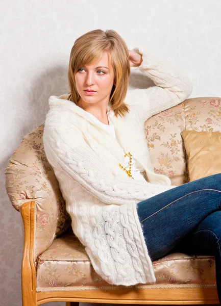 Giovane donna si siede su un divano — Foto Stock